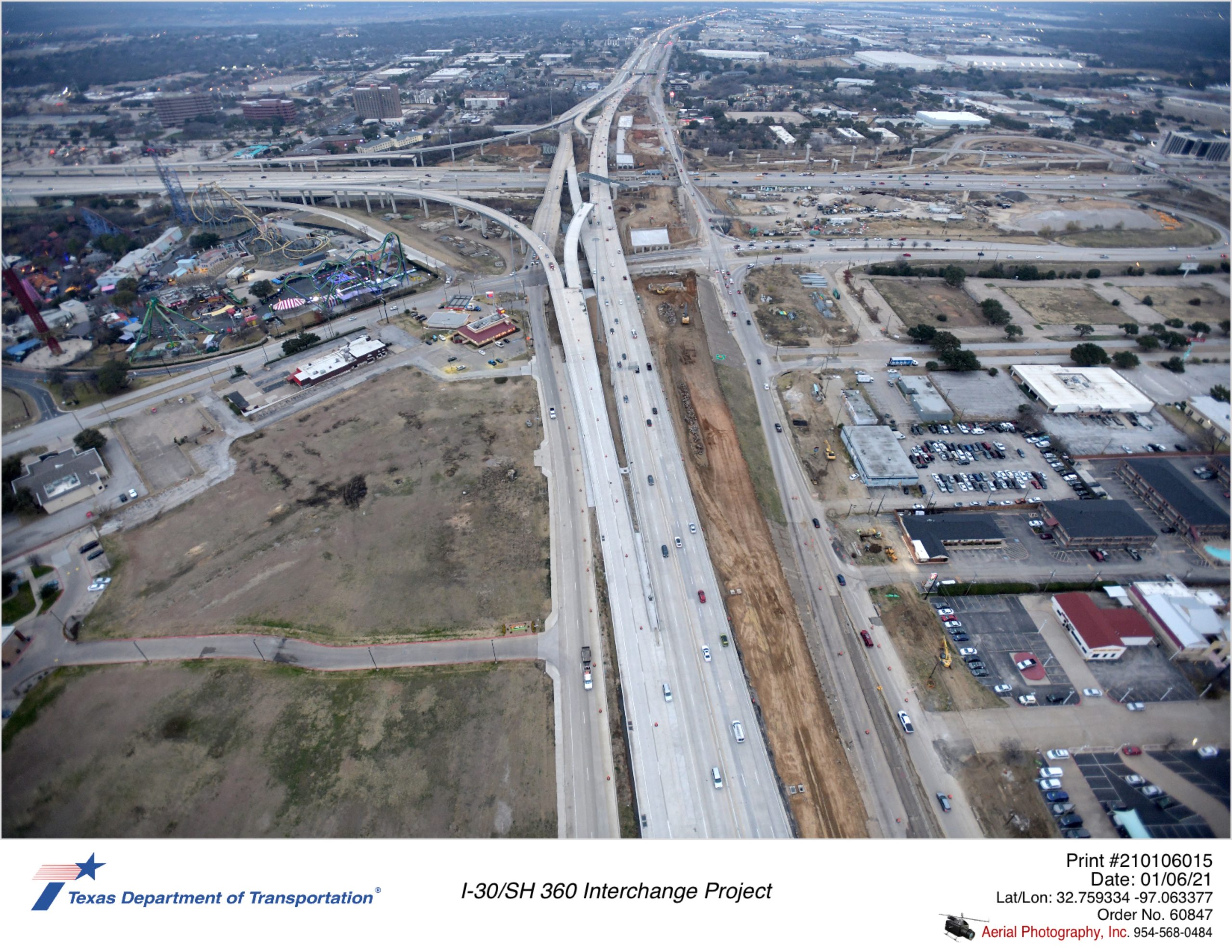 Over SH 360 looking north with I-30 interchange in background. SH 360 mainlane traffic shown on west side of alignment with large open space for new northbound mainlane construction.